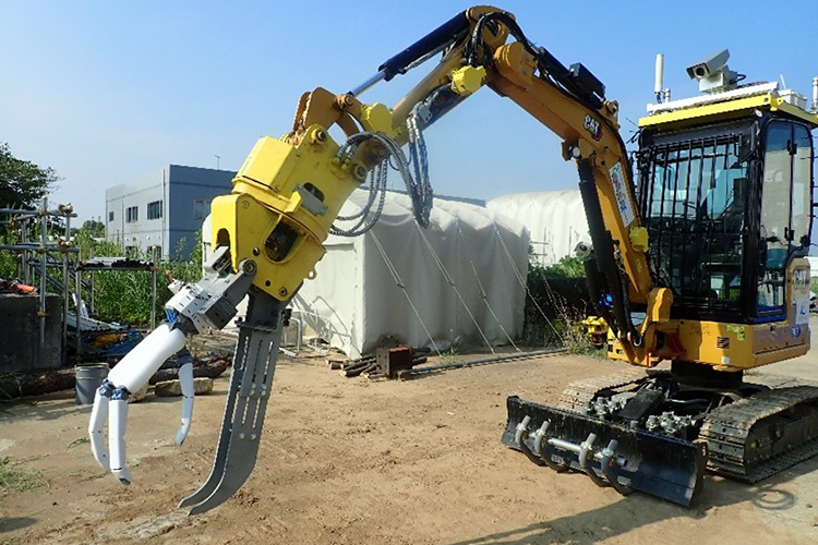 写真-2　ロボットハンドとフォークグラブ付きバックホウ